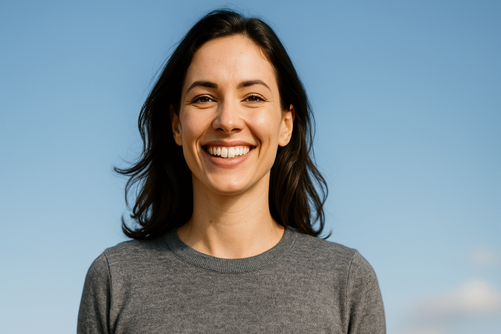 Une femme souriante regarde la caméra, rayonnante de confiance et de sérénité.